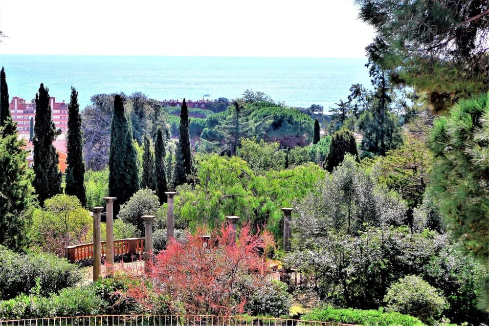 The Mediterranean seen from the villa gardens, over stone columns and cypress trees