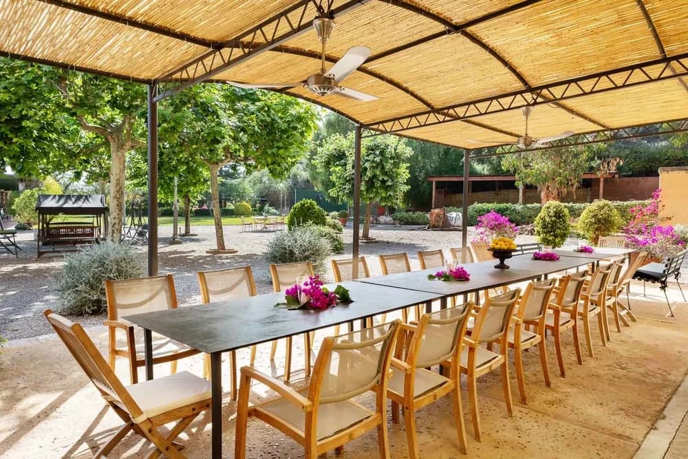 A long dining table for twenty under a reed pergola in the garden, set with bougainvillea and a bowl of lemons