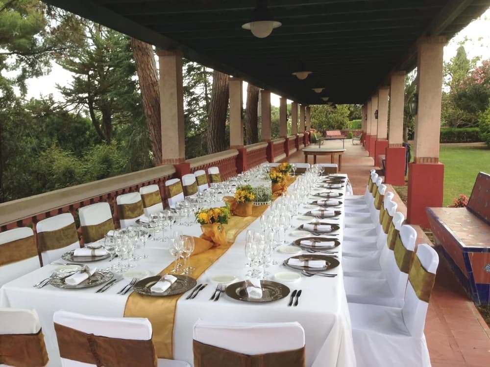 A banquet table dressed in white and gold running the length of the villa's columned veranda